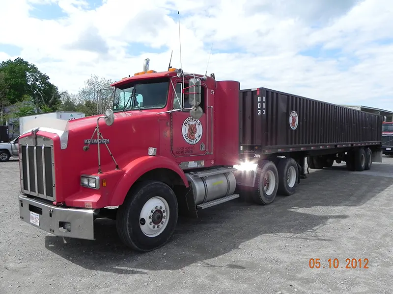 Red Kenworth tractor pulling a cranberry trailer